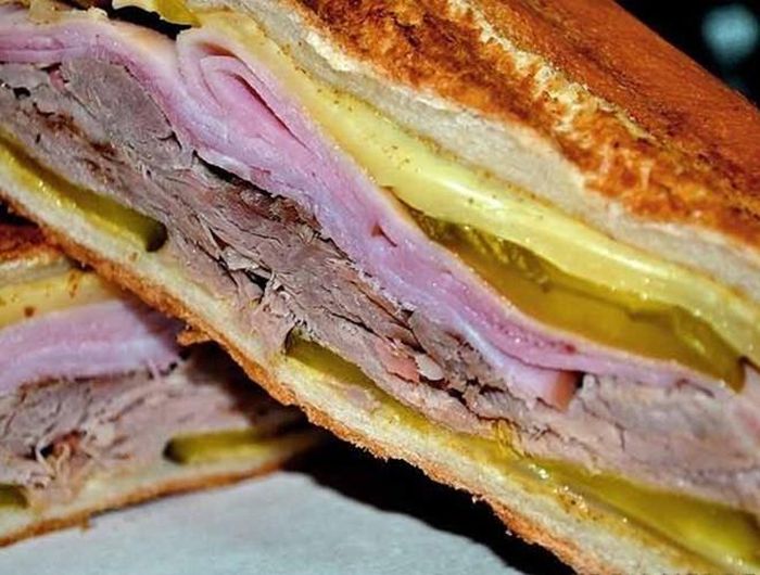  Món này bao gồm bánh mì kẹp thịt heo, thịt hầm hoặc thịt gà, phômai và xốt Mojo, có thể ăn kèm khoai tây chiên và xà lách 