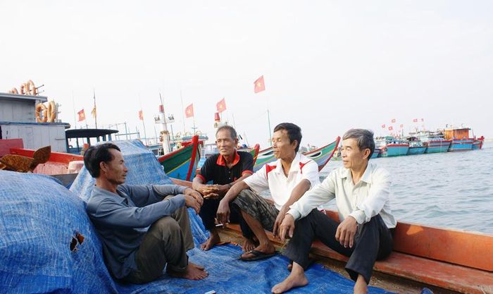 Ông Nguyễn Quốc Chinh (bìa phải) tuyên truyền, vận động ngư dân trước khi tàu cá rời bến.