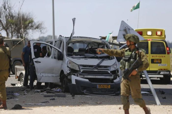 Quân đội Israel bên cạnh một chiếc xe bị dính tên lửa của Palestine. Với số lượng rocket lớn và bắn trong cùng thời điểm khiến cho có thời điểm tổ hợp Iron Dome bị quá tải, không thể đánh chặn hiệu quả. Ảnh: AP.