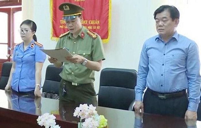 Ông Hoàng Tiến Đức (bìa phải) chứng kiến cơ quan công an tống đạt quyết định khởi tố các bị can trong vụ gian lận điểm thi