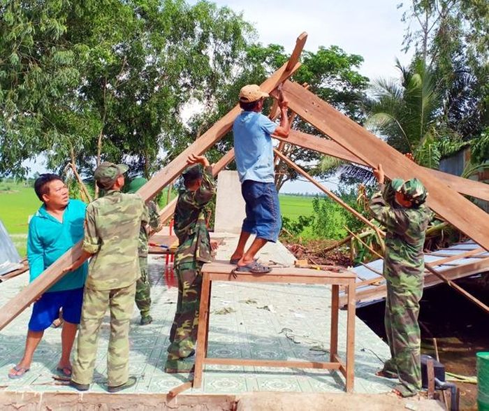 Lực lượng chức năng hỗ trợ người dân dựng lại nhà.