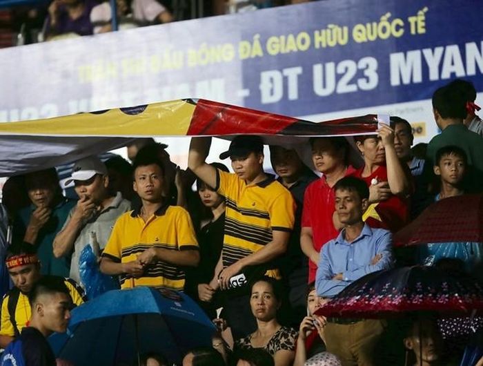 Người không có ô hay áo mưa thì dùng tạm... áp-phích quảng cáo để tránh mưa