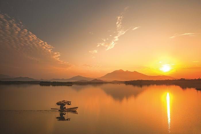 Bên cạnh cồn nhỏ lơ thơ với những tàng cây in bóng nước lung linh là một chiếc thuyền câu mỏng như chiếc lá thu khẽ khàng trôi trên mặt nước thật nhẹ như sợ làm xao động cái khoảng khắc ngưng đọng tuyệt đẹp của đất trời 