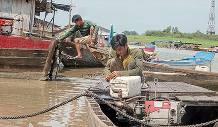 Hai người đàn ông này đang sửa máy chiếc ghe chở cá thuê. Đó là cách duy nhất họ kiếm tiền sau khi cá nuôi bị chết. 