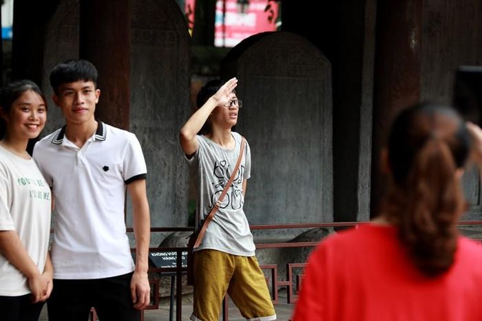 Các sĩ tử chào và chụp hình lưu niệm ở nhà bia tiến sĩ chứ không xâm phạm sờ đầu rùa như trước đây.