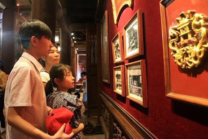 Các sĩ tử cùng người thân đứng trước tấm bảng đỏ khắc chữ “Hiền tài là nguyên khí của quốc gia” 