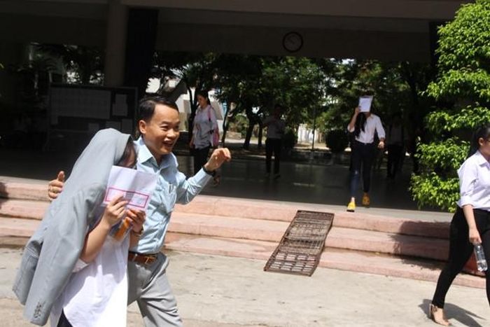  Vừa bước ra khỏi phòng thi, người cha vội cởi chiếc áo, khoác lên vai con mình che nắng. 