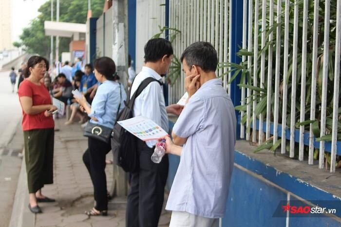 Từng nhóm phụ huynh đợi con trước cổng trường.