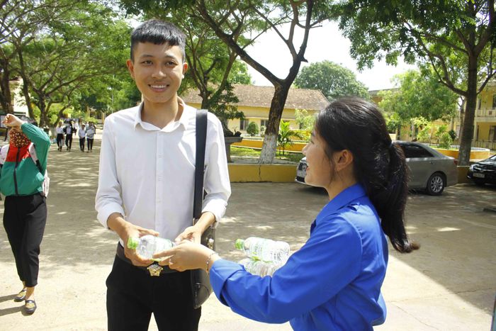 Các tình nguyện viên phát nước cho các thí sinh sau khi rời phòng thi. Ảnh: NGUYỄN TRANG