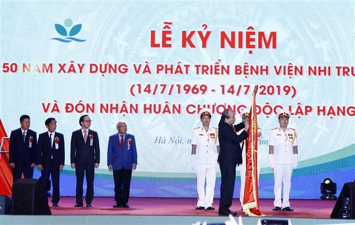 Thủ tướng Nguyễn Xuân Phúc gắn Huân chương Độc lập hạng Nhì lên cờ truyền thống của Bệnh viện Nhi Trung ương. Ảnh: Thống Nhất/TTXVN
