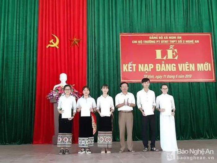 Lục Thị Doanh (áo dài trắng, bên phải) nhận quyết định kết nạp Đảng tại Trường THPT DTNT tỉnh Nghệ An. Ảnh NVCC
