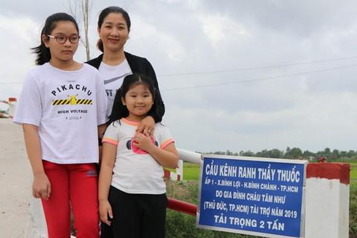 Hai bé Như Quỳnh, Tâm Như và mẹ bên cây cầu do gia đình tài trợ