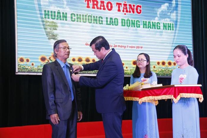 Ông Phan Việt Cường, Bí thư Tỉnh ủy, Chủ tịch HĐND, Trưởng đoàn Đại biểu Quốc hội tỉnh Quảng Nam thừa lệnh Chủ tịch nước trao tặng Huân chương Lao động hạng Nhì cho ông Phan Minh Á, Phó Chủ tịch Thường trực LĐLĐ tỉnh Quảng Nam