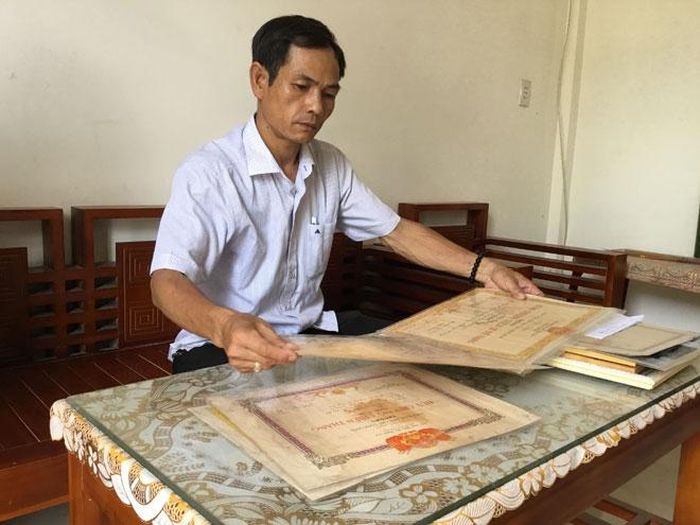 Anh Lê Xuân An đang lần giở những bằng khen, giấy khen về chiến công của cha mình. 