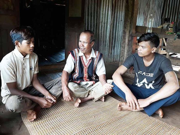 Già làng Rơ Châm Nhích (giữa) trò chuyện với thanh-thiếu niên trong làng. Ảnh: L.H