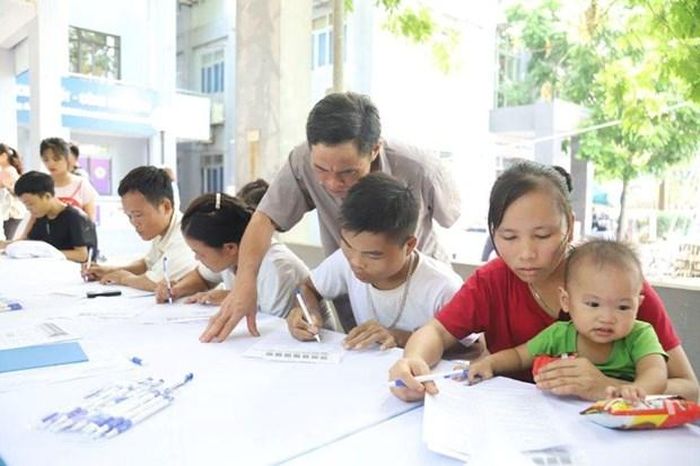 Người dân viết vào phiếu đăng ký khám sàng lọc bệnh. (Ảnh: PV/Vietnam+)