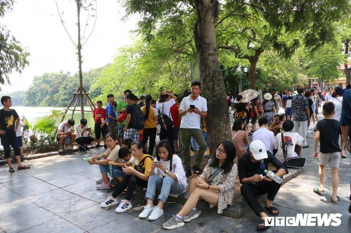  Nhiều đoàn khách sau khi đi tham quan một vòng hồ Hoàn Kiếm tranh thủ ngồi dưới các gốc cây ven hồ đế tránh nắng. 