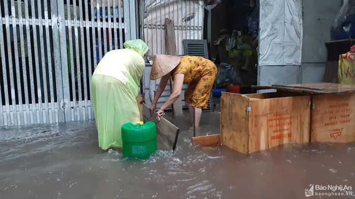 Lo ngại nước vào nhà, người dân trên đường Trần Hưng Đạo phải che chắn trước cổng và kê cao hàng hóa, tài sản. Ảnh: Thành Cường