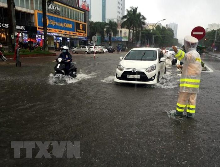 Lực lượng Cảnh sát giao thông, Công an thành phố Vinh tiến hành phân luồng, hướng dẫn các chủ phương tiện không di chuyển vào các tuyến đường bị ngập. (Ảnh: Tá Chuyên/TTXVN)