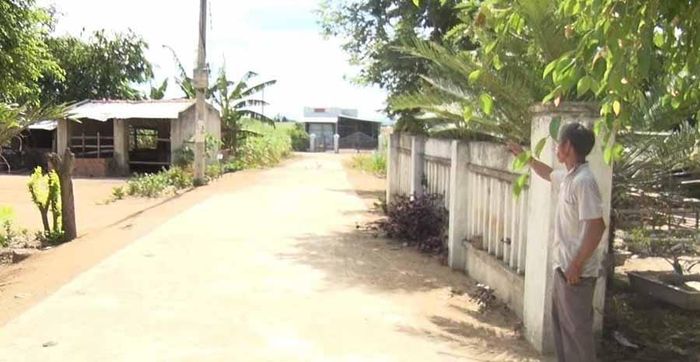 Ông Đinh Xăm chỉ về con đường được ông và người dân trong làng hiến đất, đóng góp ngày công mở rộng và bê tông. Ảnh: Hồng Thương