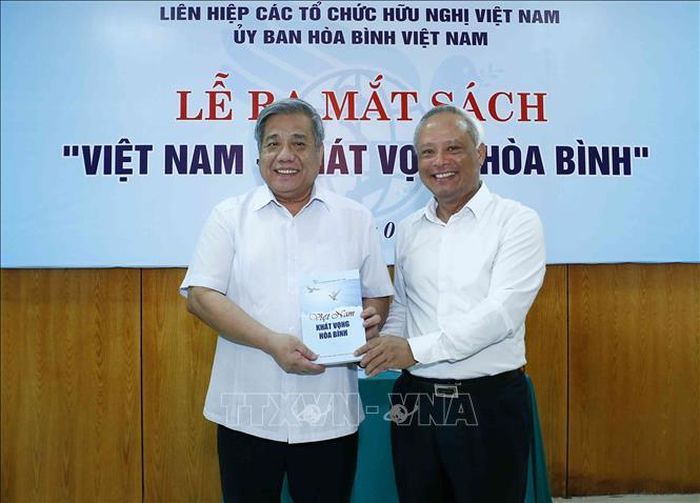 Đồng chí Uông Chu Lưu, Ủy viên Trung ương Đảng, Phó Chủ tịch Quốc hội, Chủ tịch Ủy ban Hòa bình Việt Nam tặng sách cho các đại biểu. Ảnh: Văn Điệp/TTXVN