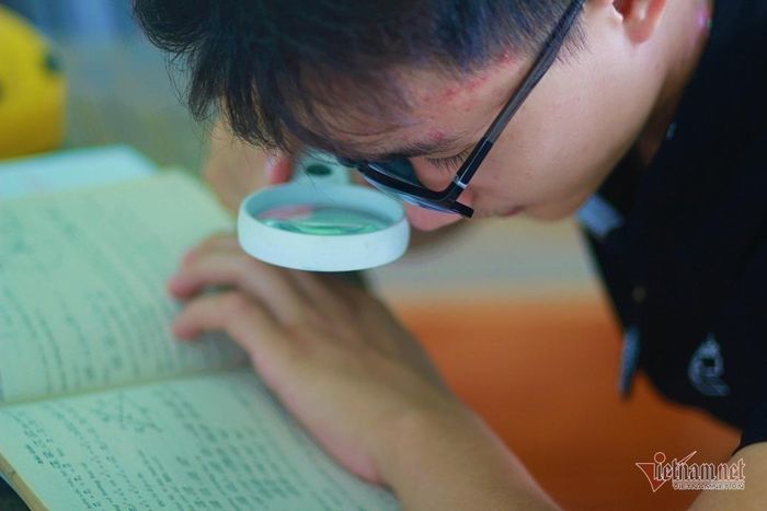 Nguyễn Văn Trung phải dùng kính lúp để phóng to chữ mới có thể đọc sách.