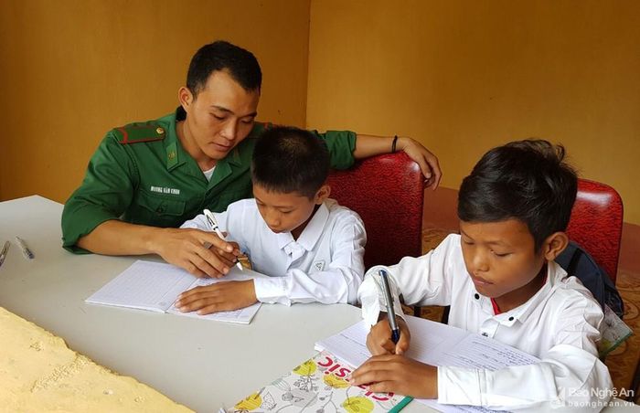 Chiến sỹ Đồn Biên phòng Keng Đu theo dõi, kèm cặp "2 con" học bài. Ảnh: Thành Chung