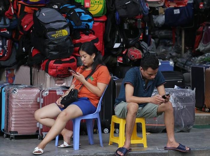 Những người bán hàng trên những tuyến phố tranh thủ lướt điện thoại mặc kệ dòng xe xuôi ngược.