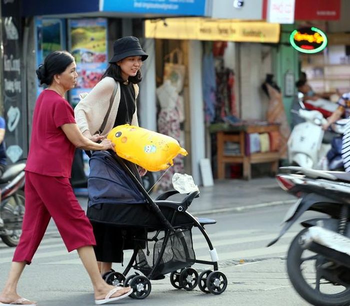 Trẻ nhỏ được người lớn mang ra đường phố tắm nắng.