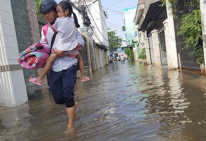 Nhiều phụ huynh bỏ xe máy bên ngoài đường Mậu Thân, lội bộ bồng con đến trường.