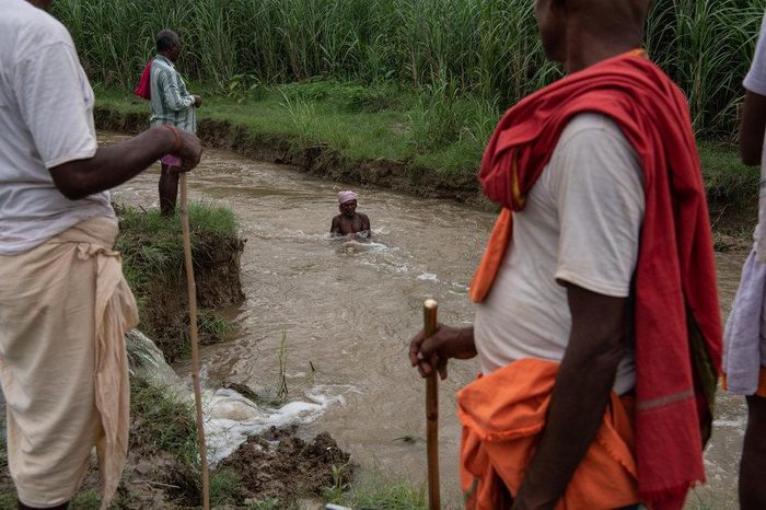 Đàn ông đánh cá ở suối do lũ sông Baghmati dọc biên giới Ấn Độ - Nepal. Ảnh: New York Times. 