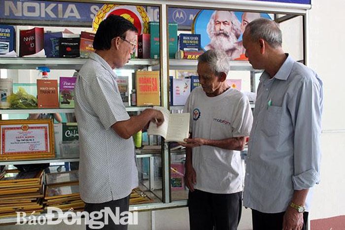 Bí thư Chi bộ ấp 2, xã Gia Canh Biện Hữu Mới (bìa trái) giới thiệu tủ sách cho người dân. Ảnh: L.Na