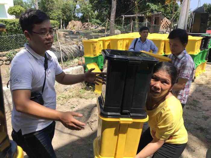 Mỗi người dân nhận giỏ cói và thùng phân loại rác tại nguồn. Ảnh: NGUYỄN TRANG