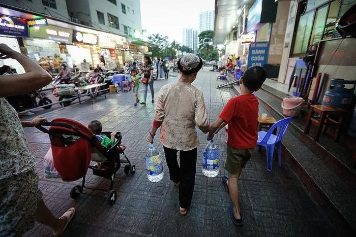 Bà và cháu nội cùng đi mua nước sạch về sử dụng sau khuyến cáo của UBND Thành phố Hà Nội
