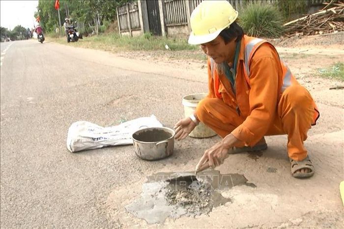 Ông Võ Văn Có vá ổ gà trên đoạn đường liên xã thuộc địa phận xã Gia Canh. 