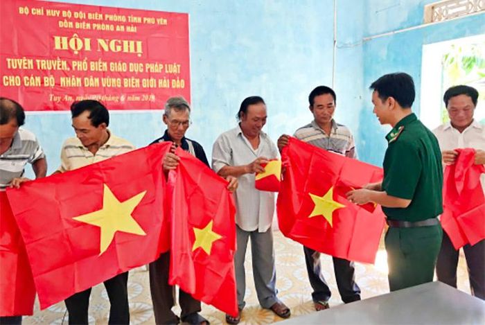 Cán bộ Đồn Biên phòng An Hải tặng cờ Tổ quốc cho ngư dân.
