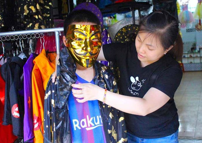 Chị Lý Bội Quân (quản lý G.A.D Shop) giúp khách hàng thử trang phục Halloween. Ảnh: Mộc Trà