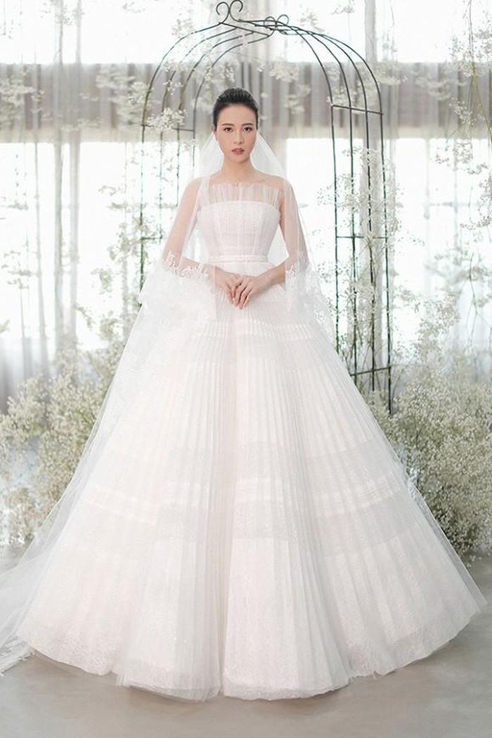 Hai bộ cánh còn lại được Đàm Thu Trang lựa chọn mặc trong ngày trọng đại đến từ nhà thiết kế Chung Thanh Phong. Khi đón khách đến tiệc, cô diện chiếc váy có phom dáng cúp ngực quyến rũ, bên ngoài được phủ bằng những đường xếp ly. Được biết, Chung Thanh Phong cùng các thợ lành nghề đã thêu họa tiết, đính kết đá pha lê, đá swarovski bằng tay trong 3 tháng liên tục.