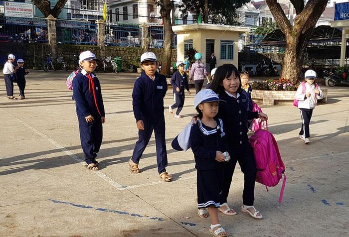 Hàng ngày, học sinh khối lớp 4 và khối lớp 5 sẽ ra tận cổng trường đón và xách cặp cho học sinh khối lớp 1 và khối lớp 2. Ảnh: T.Chu