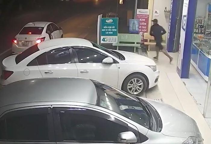 Thủ phạm mặc áo đen lao nhanh ra ôtô tẩu thoát. Ảnh: Cắt từ camera. 