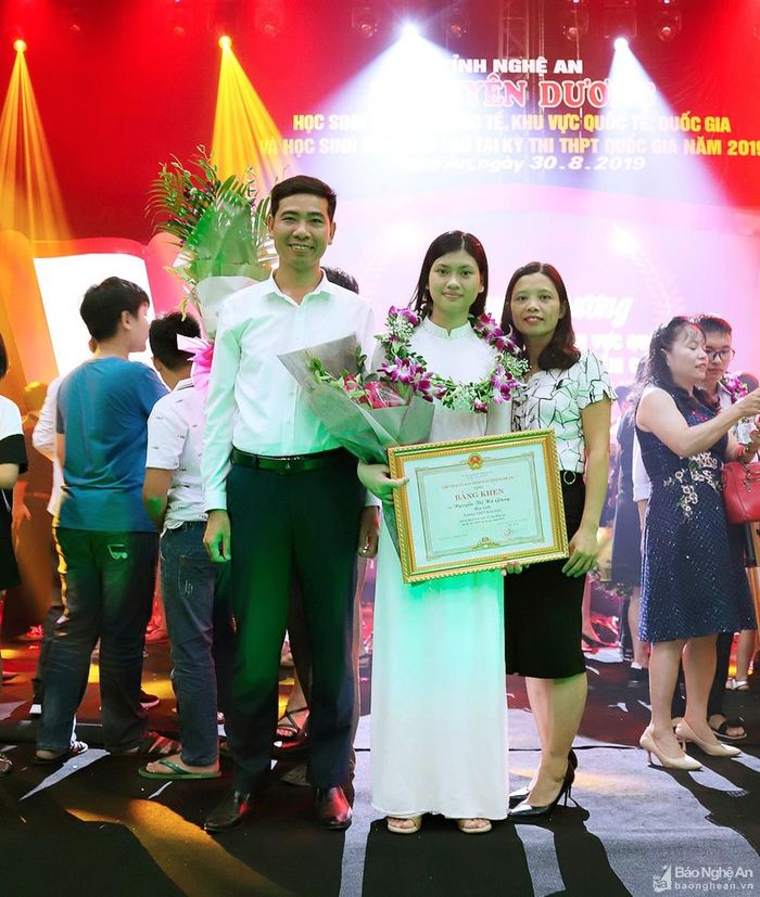 Đại diện Ban Giám hiệu nhà trường chúc mừng em Nguyễn Thị Hà Giang tại buổi lễ tuyên dương học sinh đạt thành tích cao năm học 2018 - 2019 do UBND tỉnh tổ chức. Ảnh: Minh Tuấn