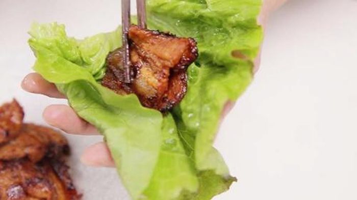 Khi thưởng thức món sỏi mầm, bạn chỉ cần cuốn thịt lợn nướng vào rau xà lách cùng các loại rau thơm khác rồi chấm nước mắm tỏi ớt. Hương vị của món ăn này được tạo nên bởi sự kết hợp hài hòa giữa vị ngọt của thịt heo rừng, quyện với rau sống tươi mát và nước mắm chua cay, đậm đà. Ảnh: Nấu ăn ngon.