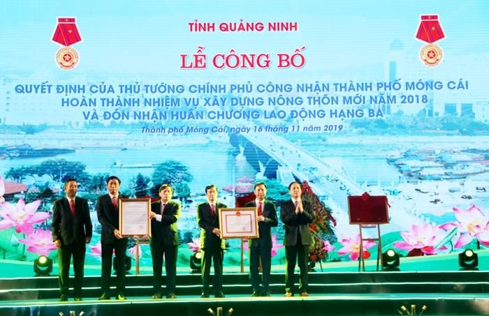 Ông Đặng Huy Hậu, Phó Chủ tịch Thường trực UBND tỉnh Quảng Ninh (bên phải ngoài cùng) trao quyết định của Thủ tướng Chính phủ công nhận TP. Móng Cái hoàn thành nhiệm vụ xây dựng MTM năm 2018 và Huân chương Lao động Hạng Ba cho đảng bộ, chính quyền và nhân dân TP. Móng Cái