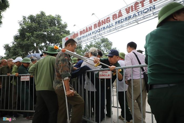 Ông Trần Văn Bình (70 tuổi, quê Hải Dương) cho biết ông cảm thấy ban tổ chức hẹp hòi khi nhiều người vất vả đi từ xa đến liên đoàn nhưng đến lượt lấy vé thì vé đã hết từ lâu. Trong ảnh là một thương binh trèo qua hàng rào để cắt ngang vào dòng người vào đăng ký lấy vé.