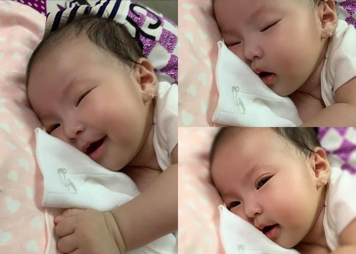 Lê Phương khoe cận cảnh hình ảnh của con gái tròn 3 tháng tuổi. Cô hạnh phúc viết: “Dạ, hôm nay con tròn 3 tháng. Thời gian qua con thấy mình thay đổi mỗi ngày, đến hôm nay thì mắt của con đã rõ mí rồi nhưng tóc thì vẫn vậy, chỉ đen hơn xíu thôi, nên lòng con ngổn ngang quá, muốn tâm sự với cô chú chút xíu. Nói chung là ngày con chào đời chỉ khoảng chừng mười mấy tiếng, tự nhiên lúc đó không biết nghĩ gì mà con cười một tràng hực hực, giống y anh hai con hồi đó! Chưa hết, từ lúc về nhà, con cười hoài luôn. Nhất là lúc vừa tỉnh giấc mắt còn đang chớp chớp vì chưa quen ánh sáng, mà nghe tiếng mẹ là con mở to mắt giống như con đang ‘nhận diện’ mẹ yêu vậy đó, đúng là mẹ rồi là con cười toe toét, nghe ‘Bông ơi’ nữa là chân con quẫy lia quẫy lịa, miệng con cười hết cỡ luôn. Thường thì khi thức dậy mà không có ai, con sẽ tự chơi một mình nhìn ngắm xung quanh. Chừng nào chơi chán con mới ư e hoặc khóc kiểu rặn rặn để thu hút sự chú ý của cả nhà. Ai chọc ghẹo là con sẽ cười, mà nhất là đang ăn sữa hay no bụng lim dim chuẩn bị ngủ là 100% con sẽ cười tươi như hoa luôn. Bởi vậy, con tên Bông cũng đúng ha cô chú. Bữa, con có nghe lỏm bà nội nói chuyện với mẹ con, con nghe loáng thoáng cái gì mà ‘à, cái miệng có duyên giống ba’. Đại ý là từ cái dáng dài sọc tới cái nết ăn ngủ, giống y ba con hà, chắc là mẹ con sắp giàu rồi đó”.