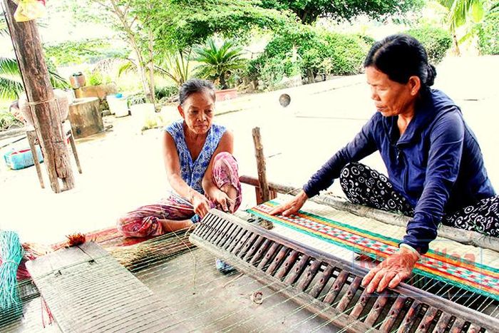  Bà Nguyễn Thị Trang (bên trái) đang kết hợp với người hàng xóm để dệt chiếu. 