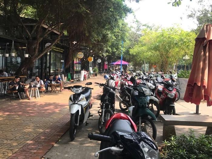 Bàn ghế quán cà phê bày ra đường nội khu công viên, xe để lộn xộn