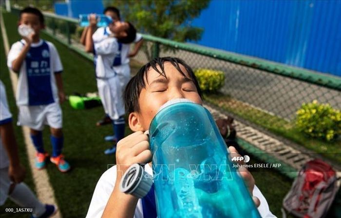 Trẻ em uống nước tại một trung tâm thể thao ở tỉnh Quảng Đông, Trung Quốc. Ảnh: AFP/TTXVN