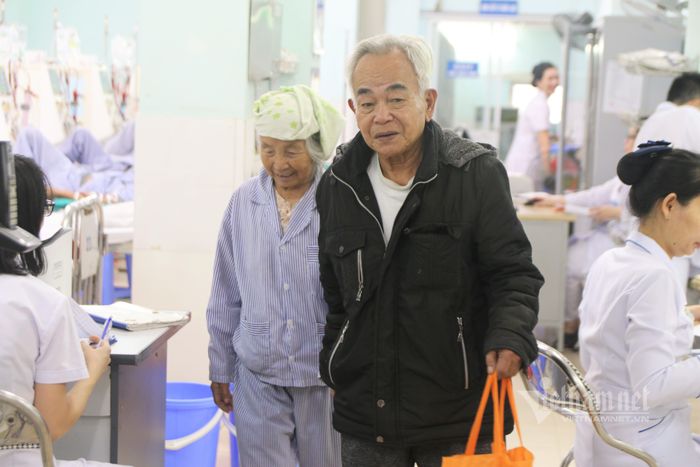Ông Phôi khéo léo đỡ vợ xuống khỏi giường bệnh, dắt bà ra về - Ảnh: Nguyễn Liên