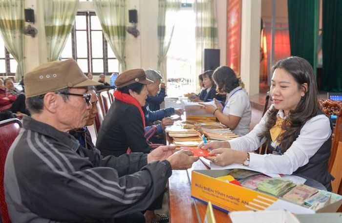 Cán bộ Bưu điện TP. Vinh chi trả chế độ người có công tại phường Hưng Phúc, thành phố Vinh. Ảnh: Thành Cường